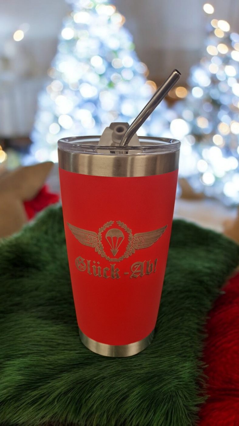 Roter Thermobecher mit Trinkhalm vor Weihnachtsbaum
